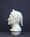 photo of plaster cast bust sculpture of Dante Alighieri with cap and high-necked robe with red book leaning against right side on black background