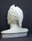 photo of plaster cast bust sculpture of Dante Alighieri with cap and high-necked robe with red book leaning against right side on black background