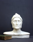photo of plaster cast bust sculpture of Dante Alighieri with cap and high-necked robe with red book leaning against right side on black background
