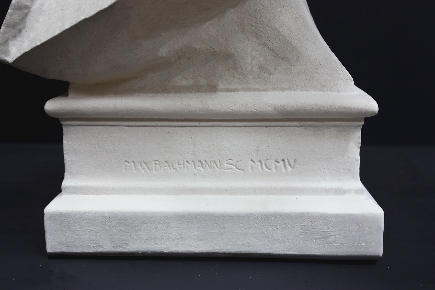 detail image of base inscriptions on a plaster sculpture bust of man, namely Abraham Lincoln, on a gray background