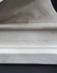 detail image of base inscriptions on a plaster sculpture bust of man, namely Abraham Lincoln, on a gray background
