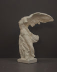 photo of plaster cast sculpture of winged, headless female figure with flowing drapery on a gray background