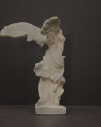 photo of plaster cast sculpture of winged, headless female figure with flowing drapery on a gray background