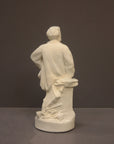 back view image of a plaster sculpture statue of a man, namely Wagner, with hand on hip leaning against a podium on a gray background