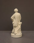 back view image of a plaster sculpture statue of a man, namely Wagner, with hand on hip leaning against a podium on a gray background