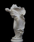 image of a plaster statue of a dancer with flowing drapery on a black background