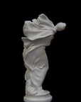 image of a plaster statue of a dancer with flowing drapery on a black background