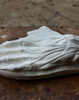 Photo of a plaster cast of a flayed hand for artist study on a wooden table with paint splatters