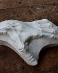 Photo of a plaster cast of a flayed hand for artist study on a wooden table with paint splatters