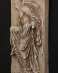 photo of cast of sculpture relief of robed figure, head now missing, reaching for her sandal in a brown patina on a dark gray background