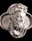 black and white photo of plaster cast sculpture of man's head in ornamental shape against black background