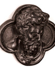 black and white photo of bronze-colored plaster cast sculpture of man's head in ornamental shape against white background