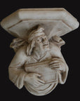 photo with black background of plaster cast sculpture of architectural bracket with a man's upper body who holds a musical instrument