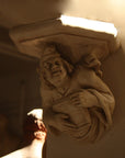photo of plaster cast sculpture of architectural bracket featuring a man's upper body who holds a musical instrument and affixed to a beige column