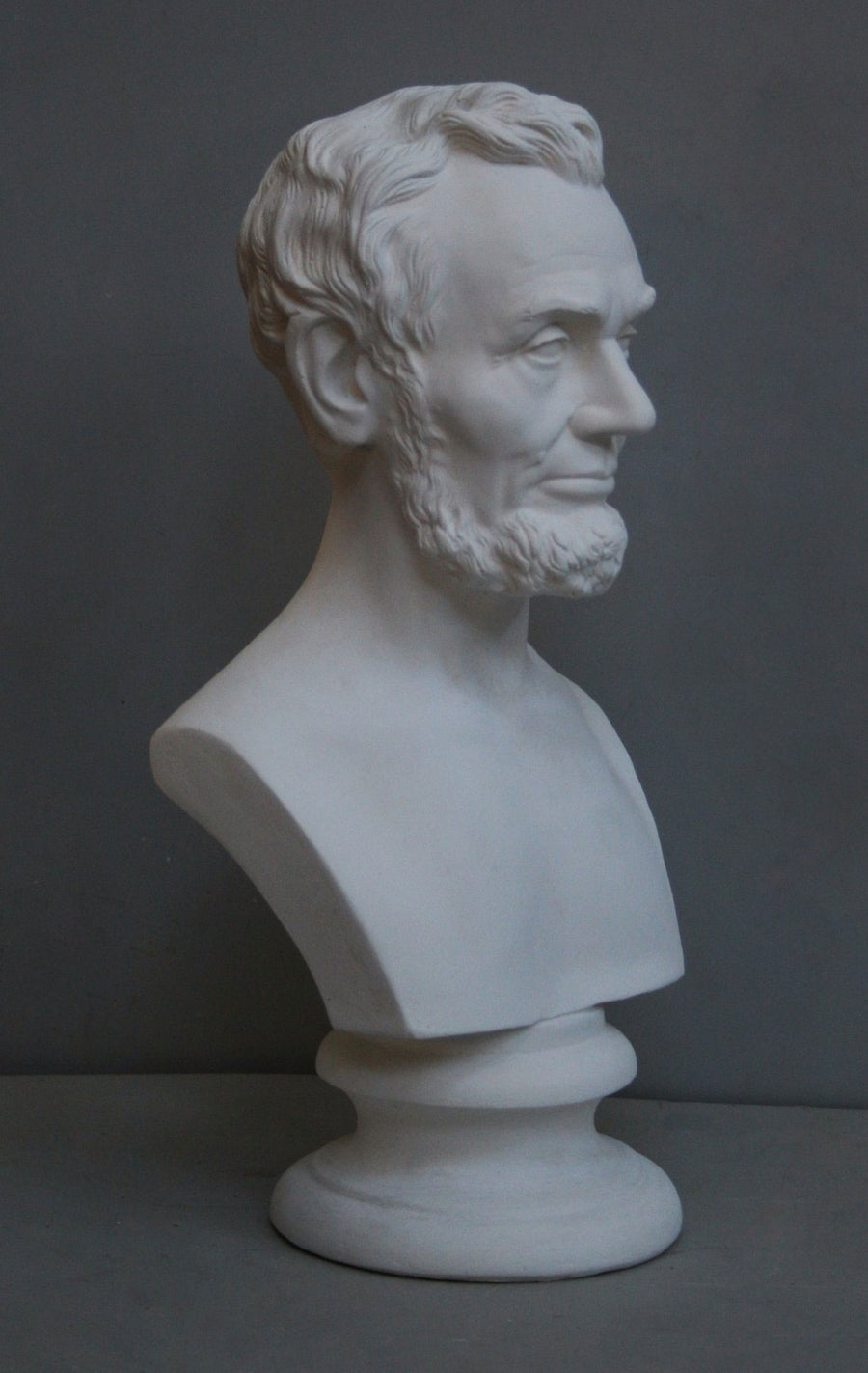photo with gray background of plaster cast bust sculpture of man with beard, namely Lincoln