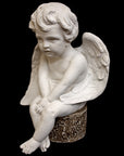 image of plaster sculpture of seated angel on a black background