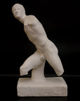 photo of white plaster cast sculpture of male figure in active pose without arms or lower legs on a base against black background