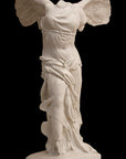 photo of plaster cast sculpture of winged, headless female figure with flowing drapery on a black background