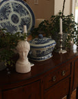 Photo of Plaster Cast sculpture bust of goddess Hebe on a dark wood bureau with blue and white China and plants