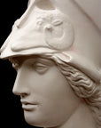 photo of plaster cast sculpture bust of female head, namely the goddess Athena, with a helmet on a black background