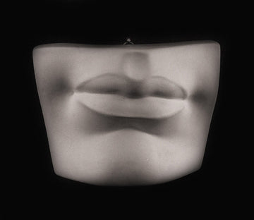 Photo of plaster cast sculpture of mouth and chin from Michelangelo's David statue on a black background