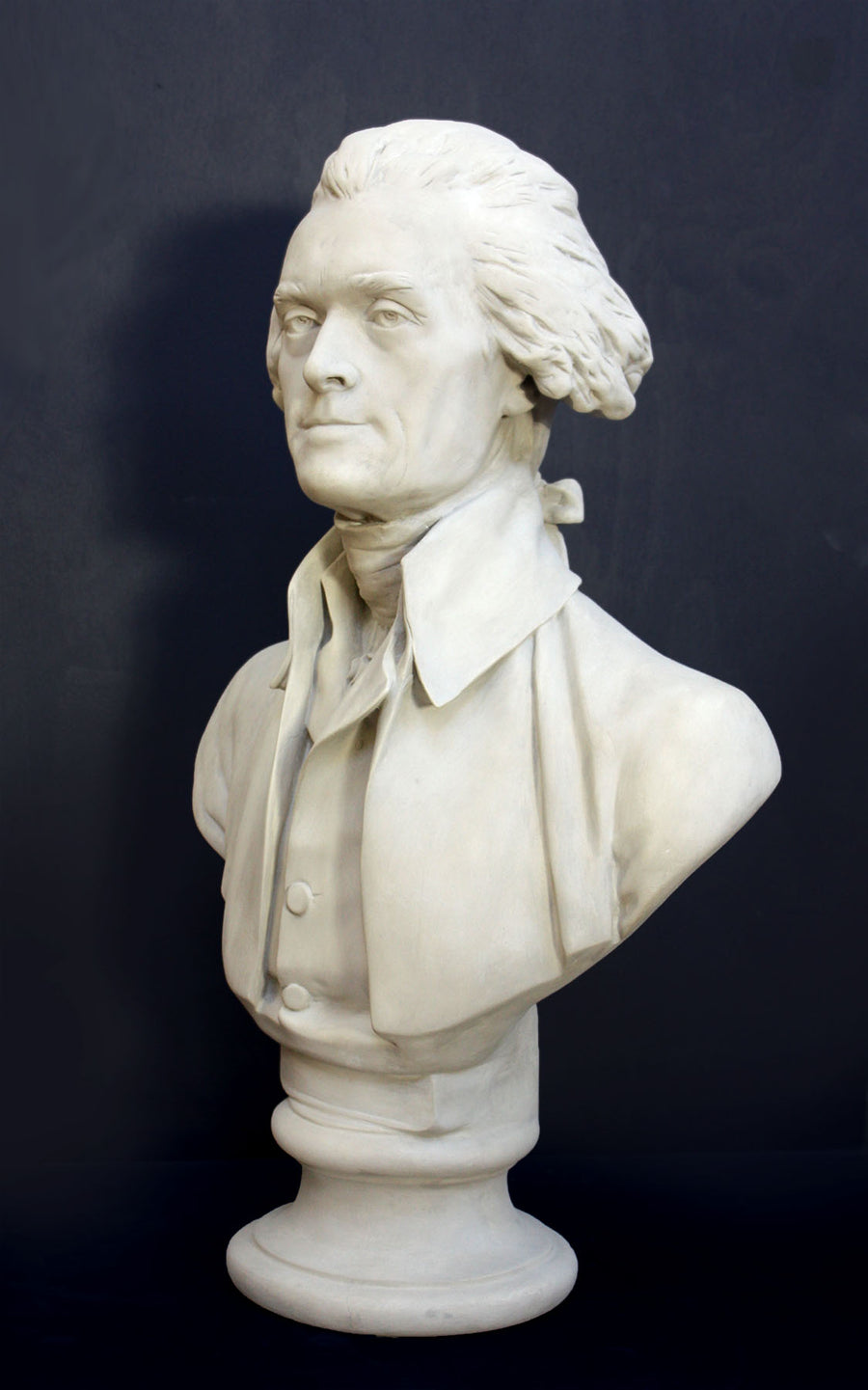Photo of plaster cast bust sculpture of man with coat and neckerchief, namely Thomas Jefferson, with dark gray background