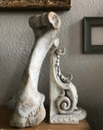 Photo of plaster cast of sculpture of Renaissance bracket leaning against a bone with empty picture frames on the wall behind