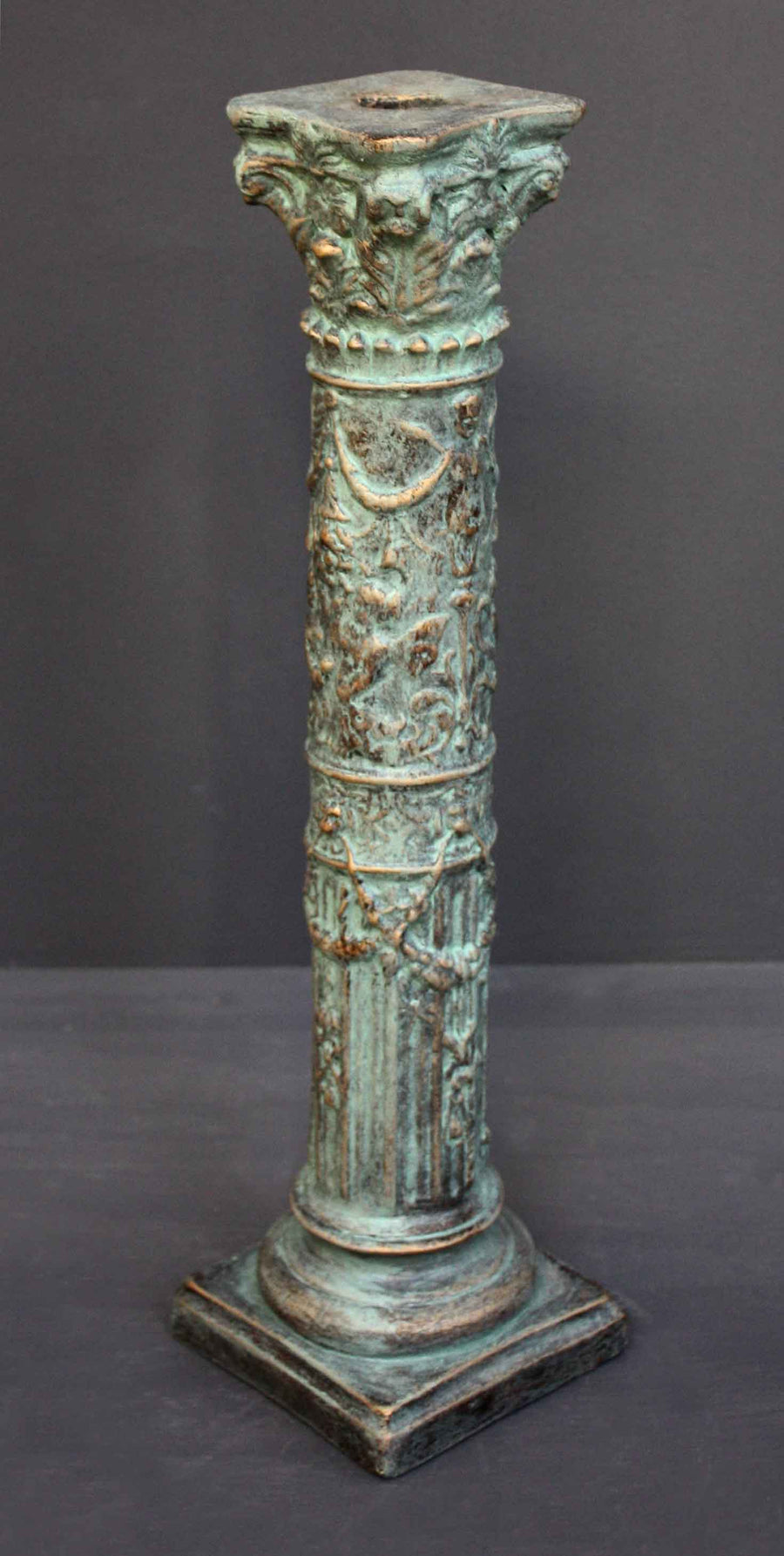 photo of plaster cast of ornamental verdigris color candlestick with gray background