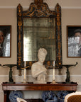 photo of plaster cast sculpture bust of Madame Recamier with high up-do and ribbon over forehead and hands crossed over chest covered in cloth on a dark wood table with bronze decorations, candlesticks, bronze framed mirror and two pictures, and blue and