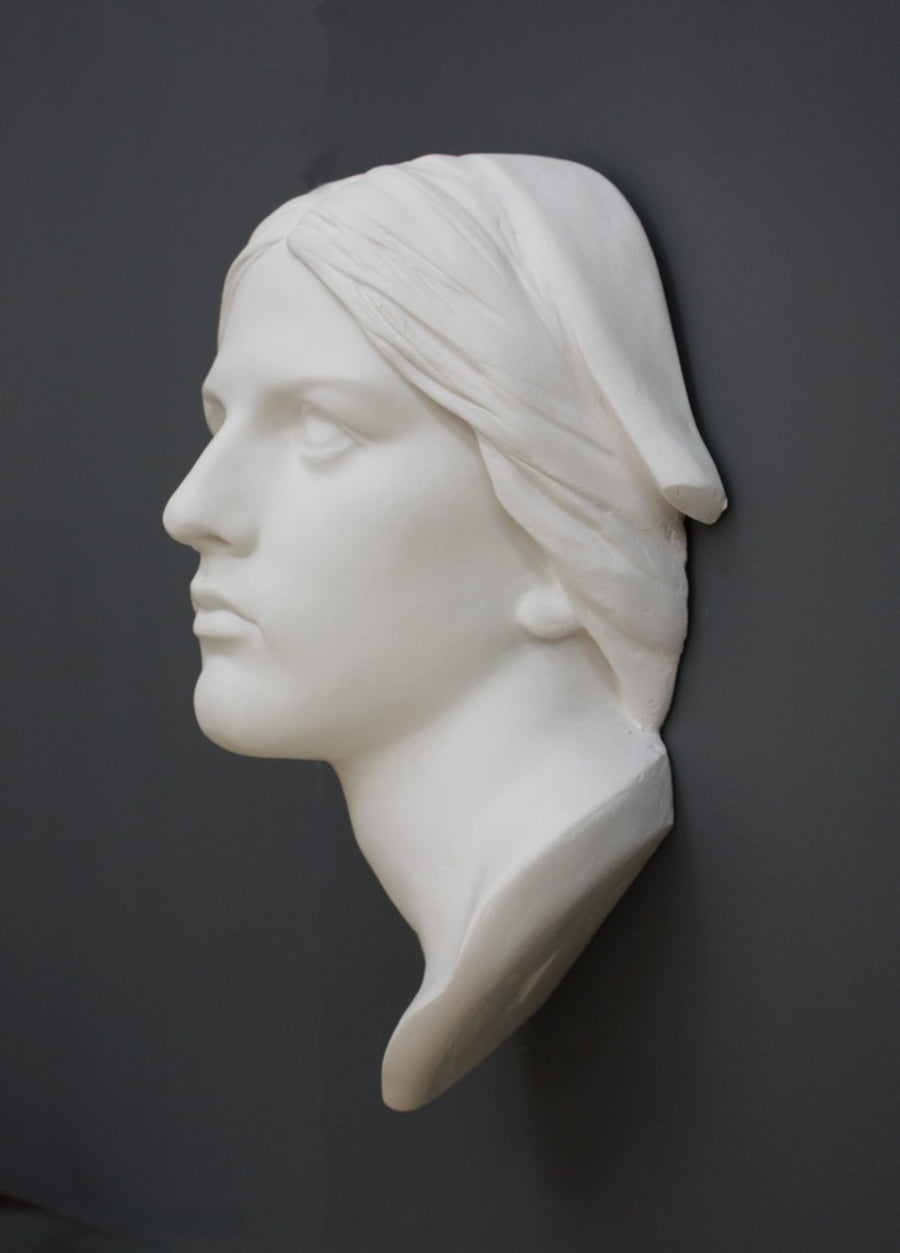 photo with gray background of plaster cast sculpture of Joan of Arc's face and portion of kerchief on head