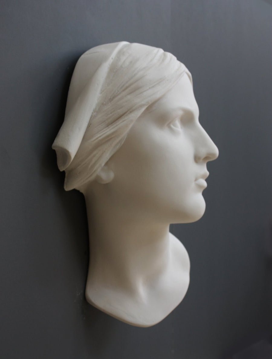 photo with gray background of plaster cast sculpture of Joan of Arc's face and portion of kerchief on head