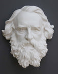 photo of plaster cast of man's head, namely Longfellow, with long hair and curly beard on gray background