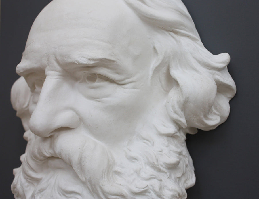 closeup photo of plaster cast of man's head, namely Longfellow, with long hair and curly beard on gray background