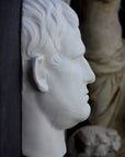 Photo of plaster cast sculpture reproduction of an Ancient Roman mask of Agrippa, side view, on a black background