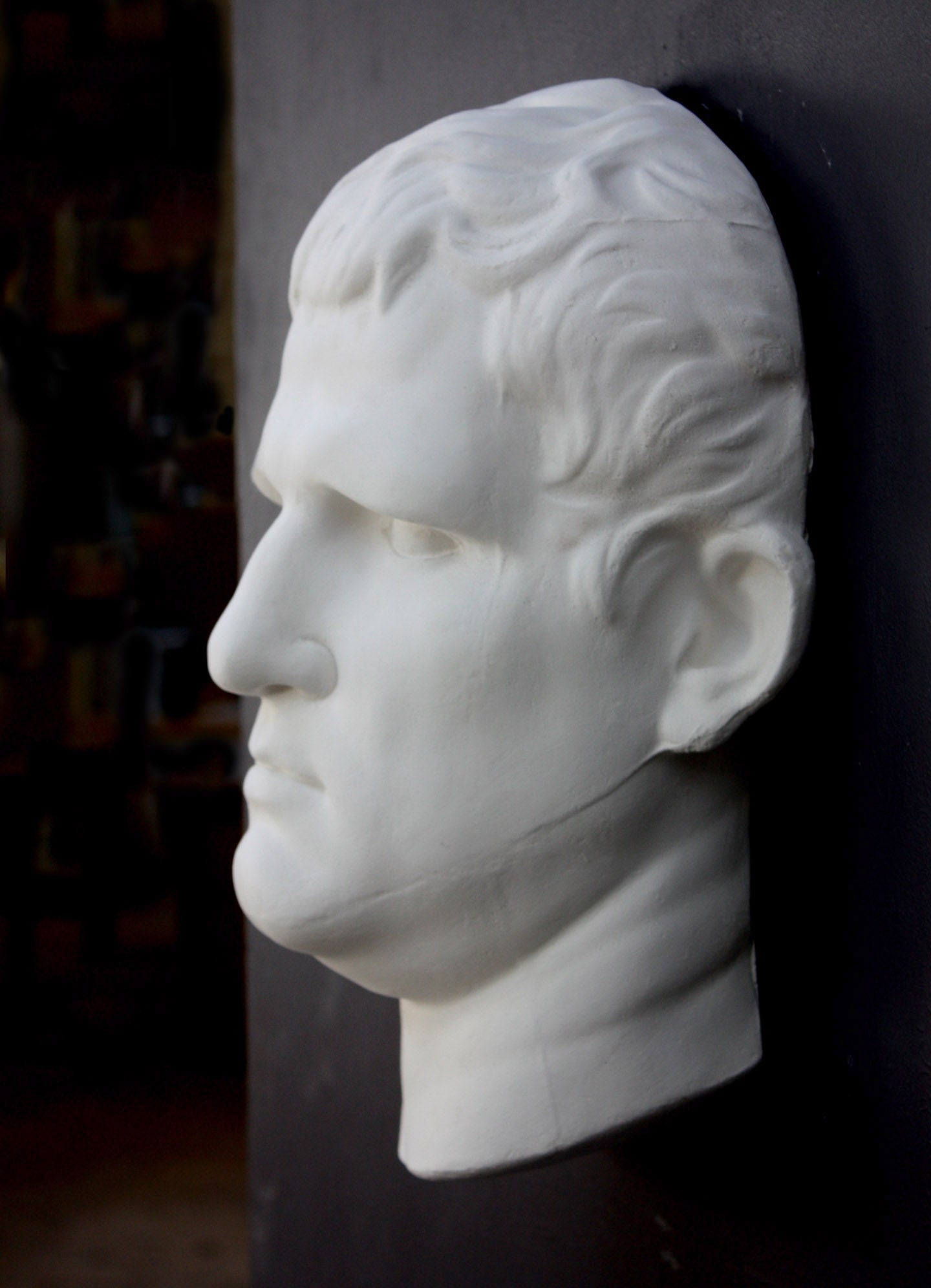 Photo of plaster cast sculpture reproduction of an Ancient Roman mask of Agrippa,  3/4 view, on a black background