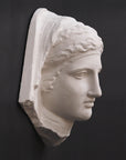 photo of white plaster cast of ancient relief sculpture of female head with headpiece and covering against dark gray background