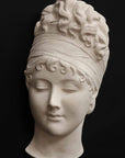 photo with black background of plaster cast sculpture of face of Madame Recamier with high up-do and ribbon over forehead