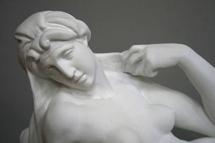 closeup photo of plaster cast of reclining female nude with a gray background