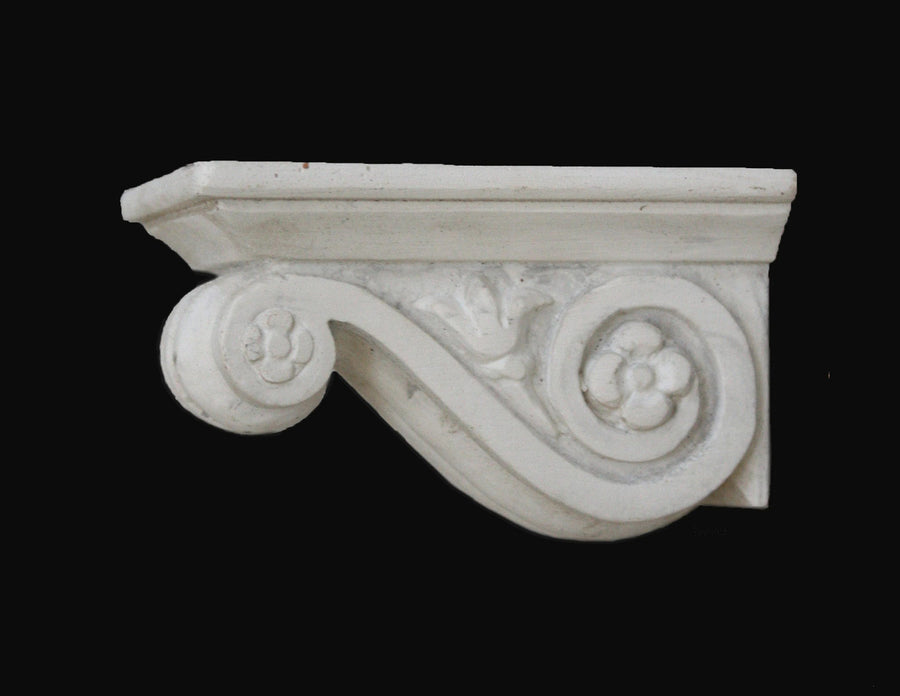 photo with black background of plaster cast of architectural bracket with scroll design