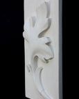 Photo of a plaster cast of a rectangle slab with a study of an acanthus leaf poited upward on the front, the whole object turned to the face the left to be seen at a 3/4 view, on a black background