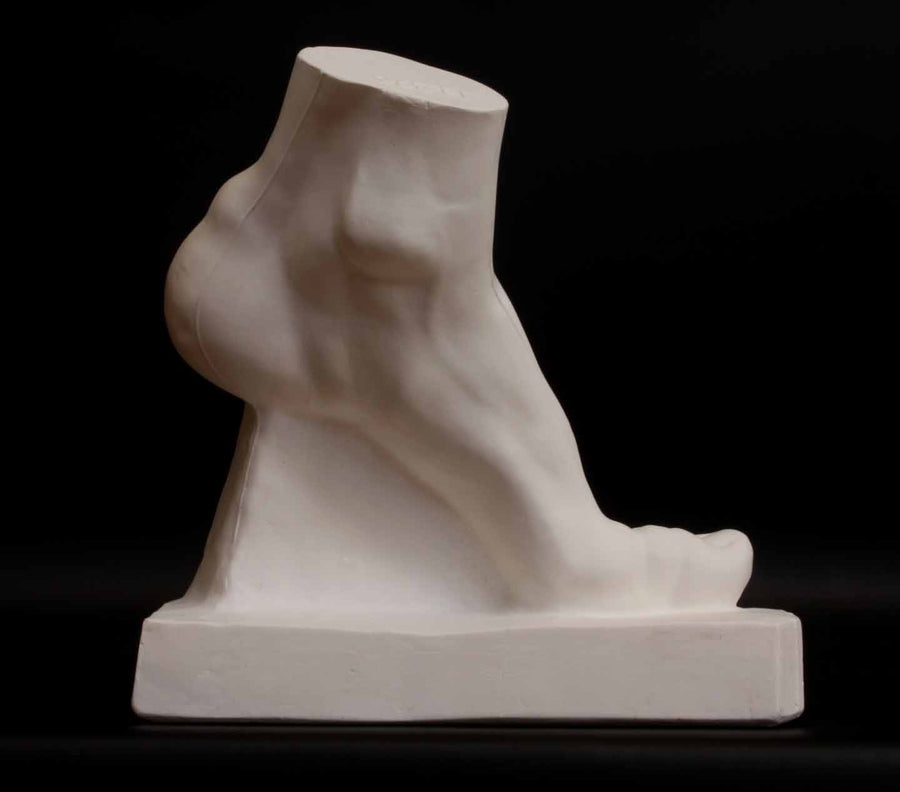 Photo of plaster cast sculpture of foot on a black background