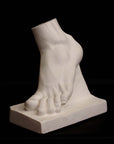 Photo of plaster cast sculpture of foot on a black background