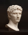 photo with black background of plaster cast of sculpted male bust, namely Augustus Caesar