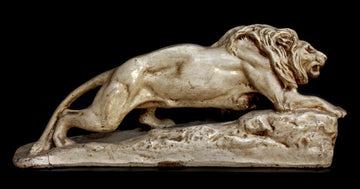 photo of off-white plaster cast sculpture of lion crawling uphill on black background