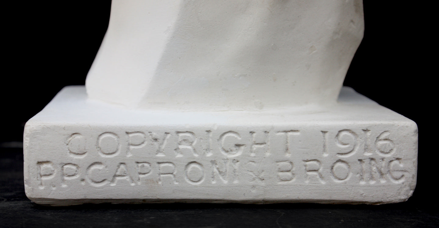 Closeup of the words "Copyright 1916, P.P. Caproni & Bro Inc" on a sculpture base of a plaster cast bust, on a black background