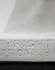 Closeup of the words "Copyright 1916, P.P. Caproni & Bro Inc" on a sculpture base of a plaster cast bust, on a black background