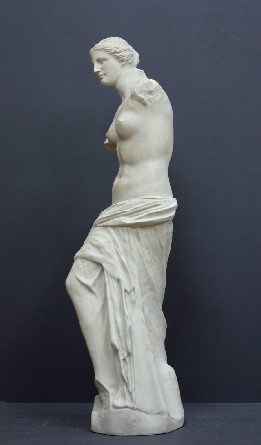 Photo of plaster cast sculpture reproduction of Venus de Melo, side view, on a grey background
