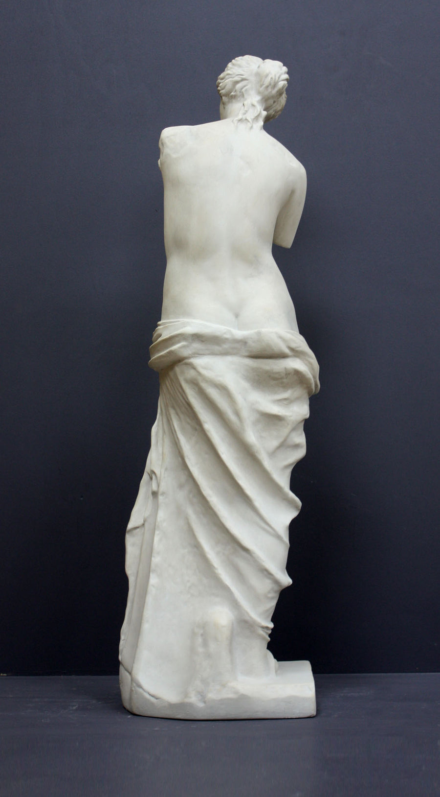 Photo of plaster cast sculpture reproduction of Venus de Melo, back view, on a grey background