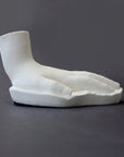 photo of white plaster cast sculpture of child hand against gray background