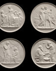 photo of four off-white plaster cast relief sculptures of male and female figures, children, cats, and dogs figuratively depicting the four seasons against black background